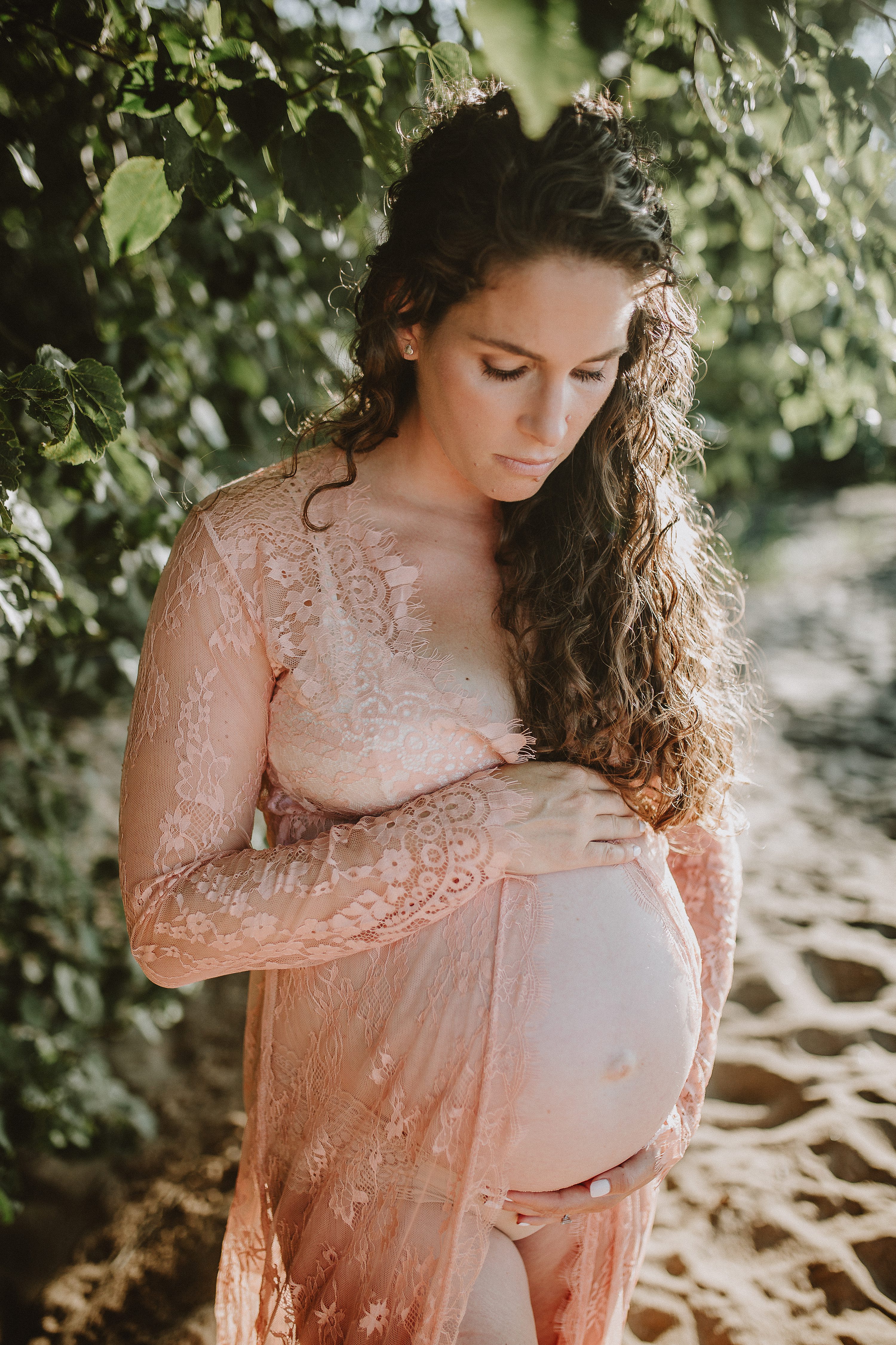 Maternity session by the river,Pregnant mother in a lace gown by the beach,PPregnant mother in a peach, lace gown by the water.,Pregnant mother in a long, lace gown holding her belly.,Pregnant woman in a peach gown near the river at sunset.