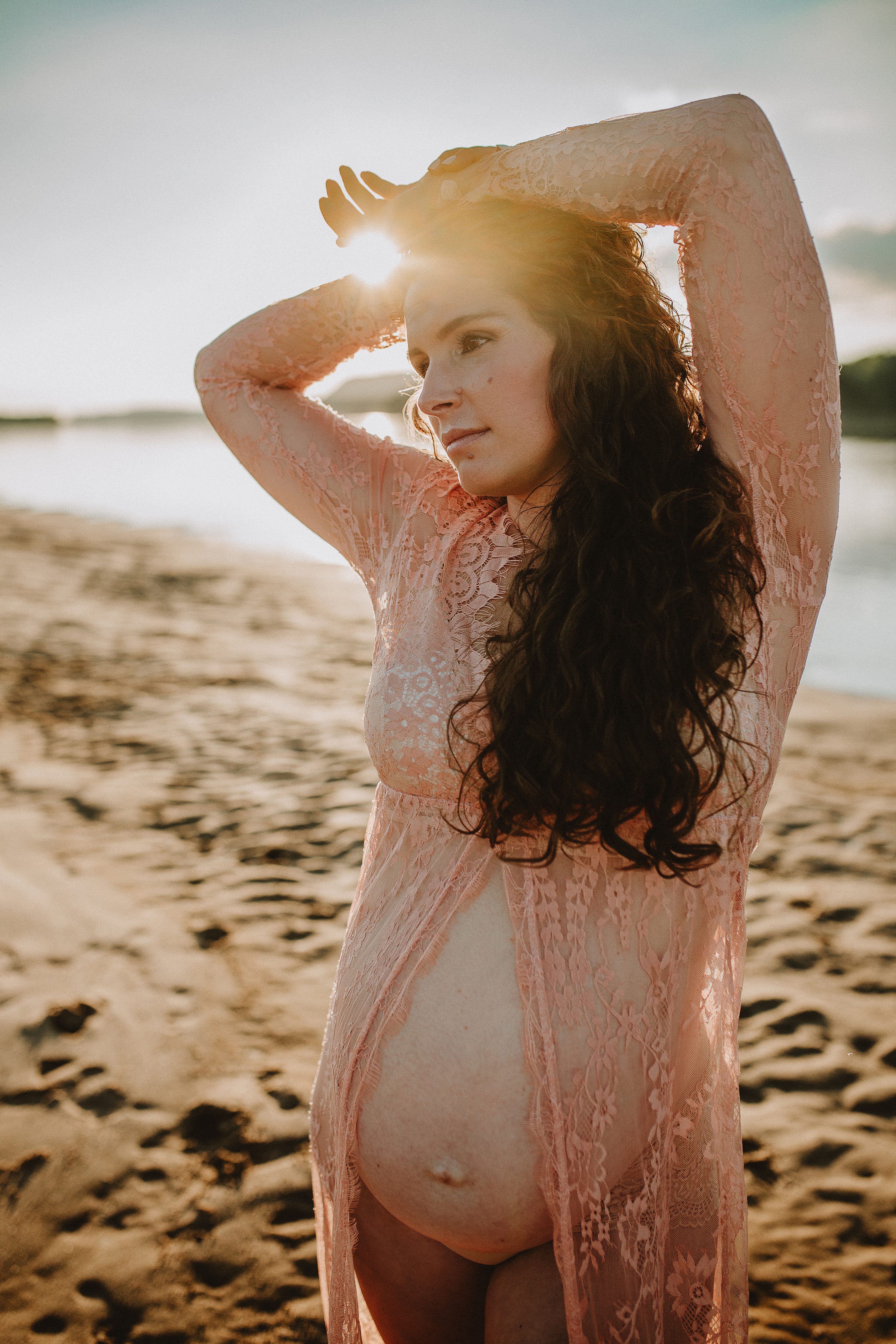 Maternity session by the river,Pregnant mother in a lace gown by the beach,PPregnant mother in a peach, lace gown by the water.,Pregnant mother in a long, lace gown holding her belly.,Pregnant woman in a peach gown near the river at sunset.