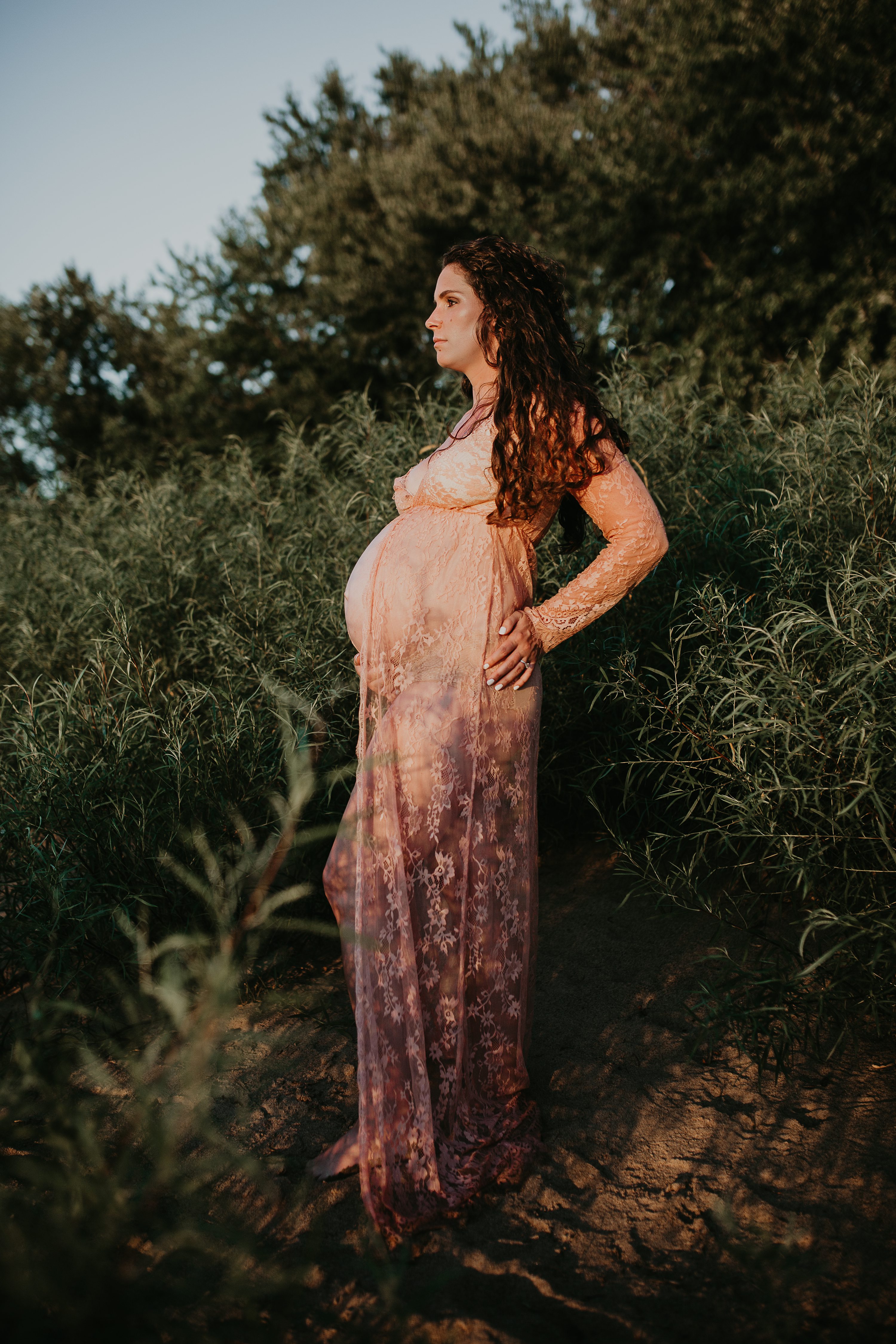 Maternity session by the river,Pregnant mother in a lace gown by the beach,PPregnant mother in a peach, lace gown by the water.,Pregnant mother in a long, lace gown holding her belly.,Pregnant woman in a peach gown near the river at sunset.