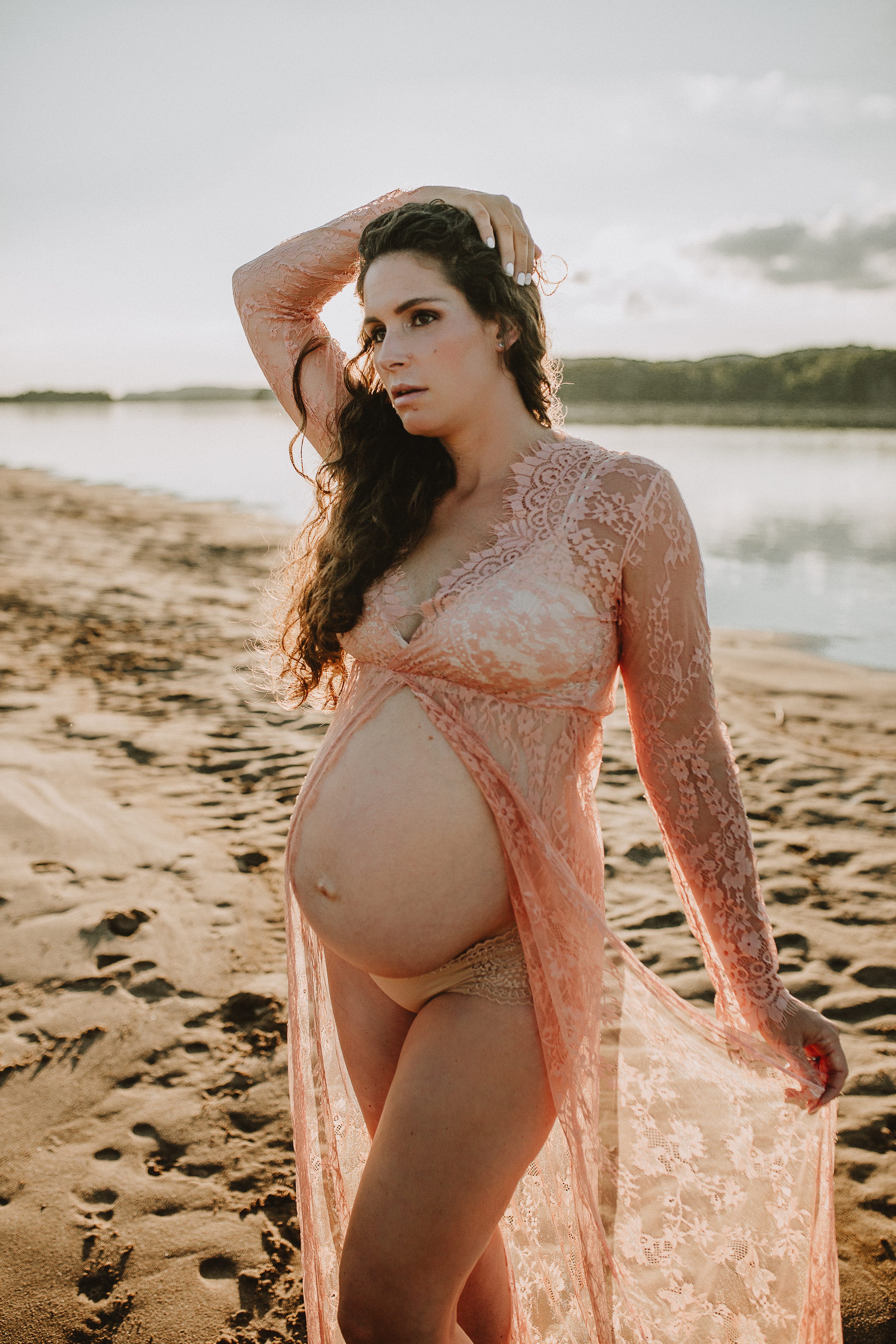 Maternity session by the river,Pregnant mother in a lace gown by the beach,PPregnant mother in a peach, lace gown by the water.,Pregnant mother in a long, lace gown holding her belly.,Pregnant woman in a peach gown near the river at sunset.