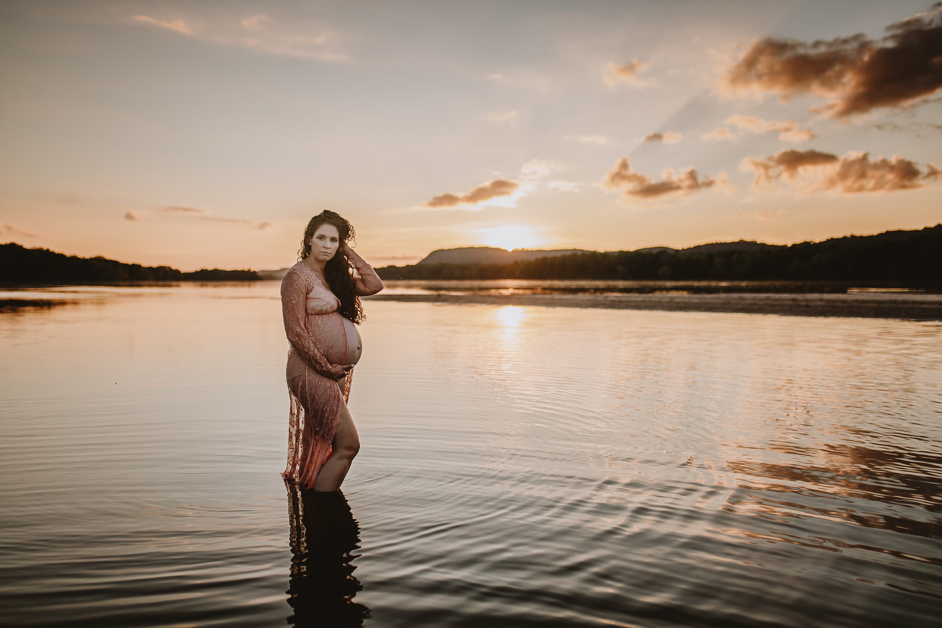 Maternity session by the river,Pregnant mother in a lace gown by the beach,PPregnant mother in a peach, lace gown by the water.,Pregnant mother in a long, lace gown holding her belly.,Pregnant woman in a peach gown near the river at sunset.