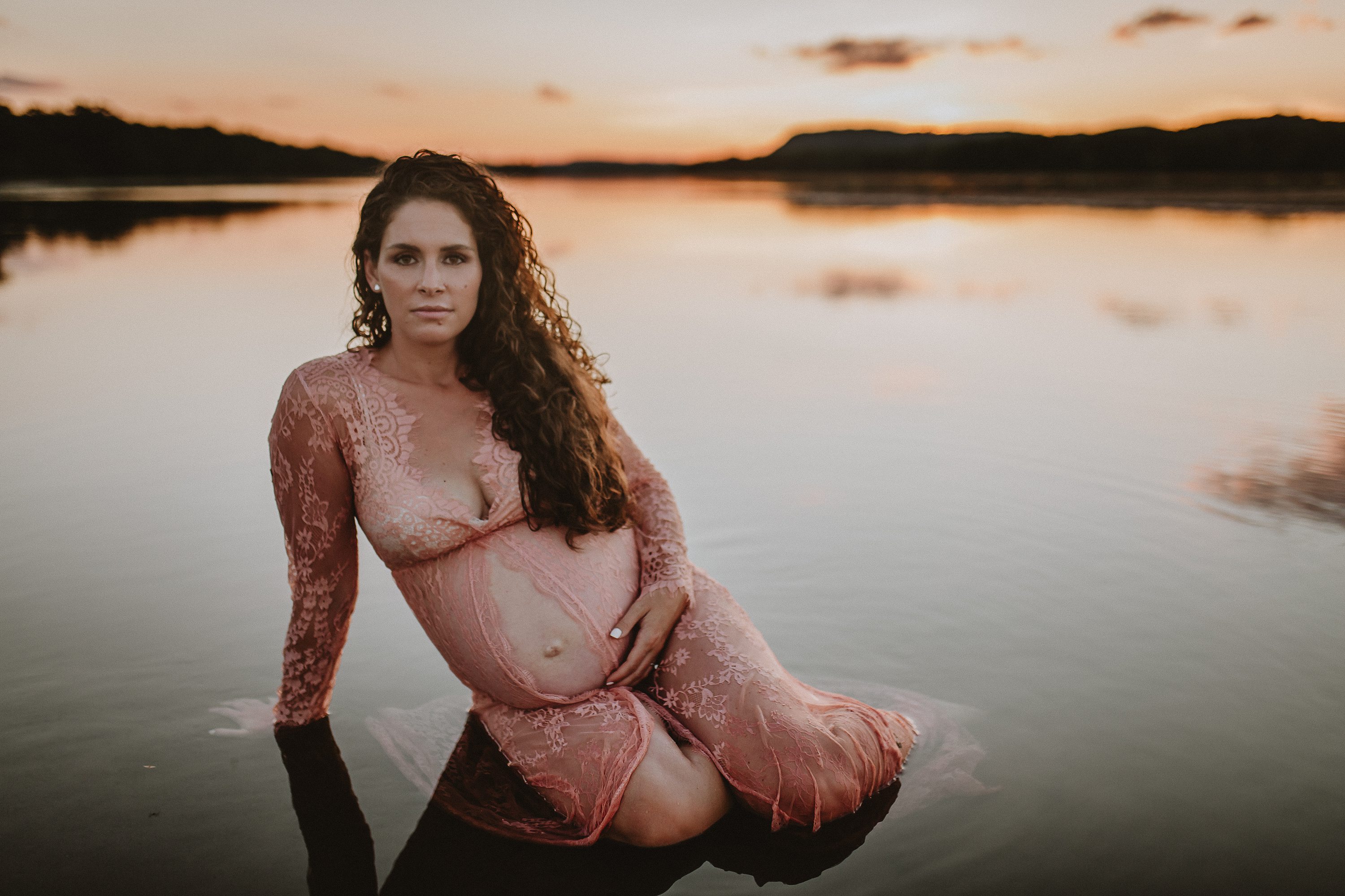 Maternity session by the river,Pregnant mother in a lace gown by the beach,PPregnant mother in a peach, lace gown by the water.,Pregnant mother in a long, lace gown holding her belly.,Pregnant woman in a peach gown near the river at sunset.
