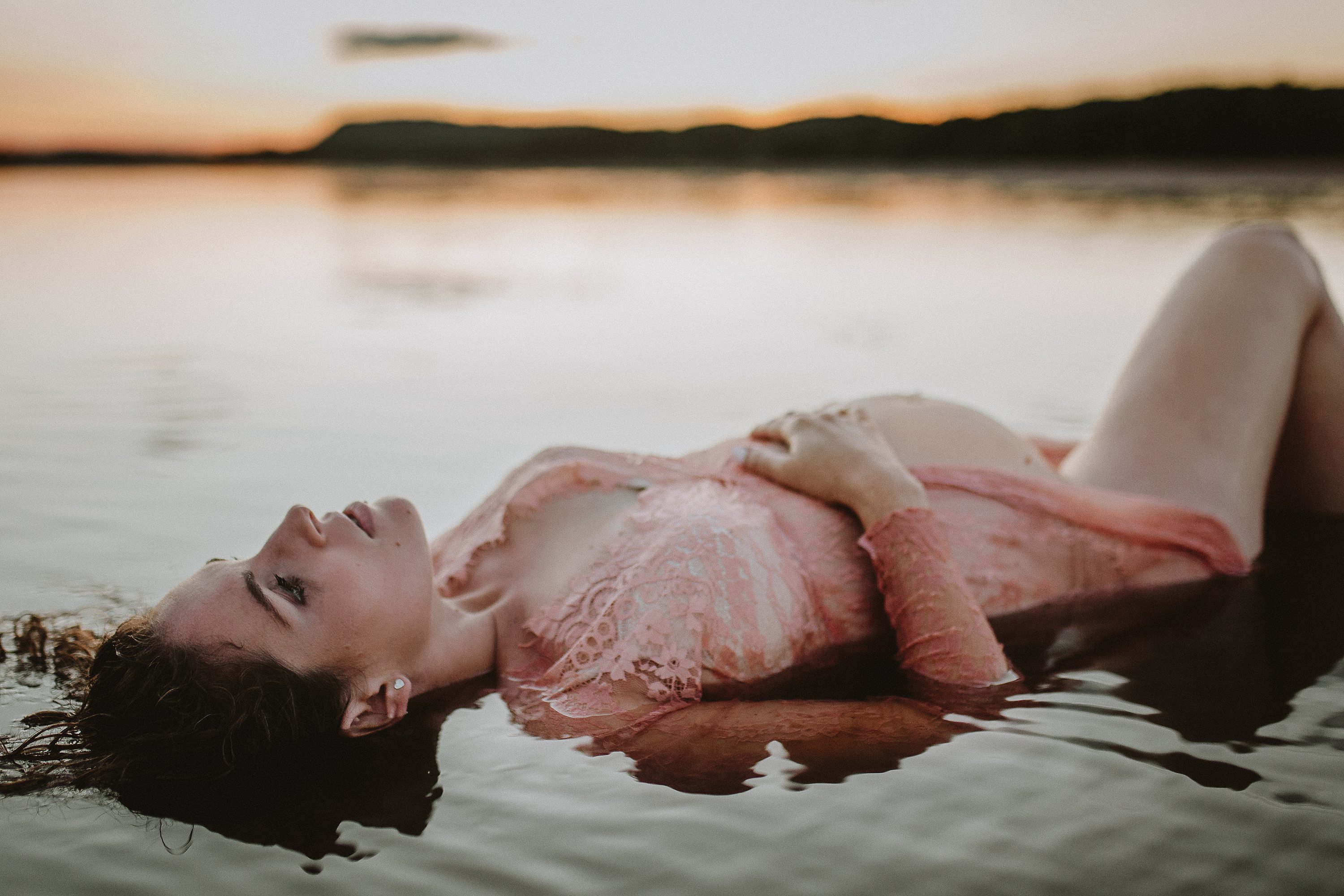 Maternity session by the river,Pregnant mother in a lace gown by the beach,PPregnant mother in a peach, lace gown by the water.,Pregnant mother in a long, lace gown holding her belly.,Pregnant woman in a peach gown near the river at sunset.