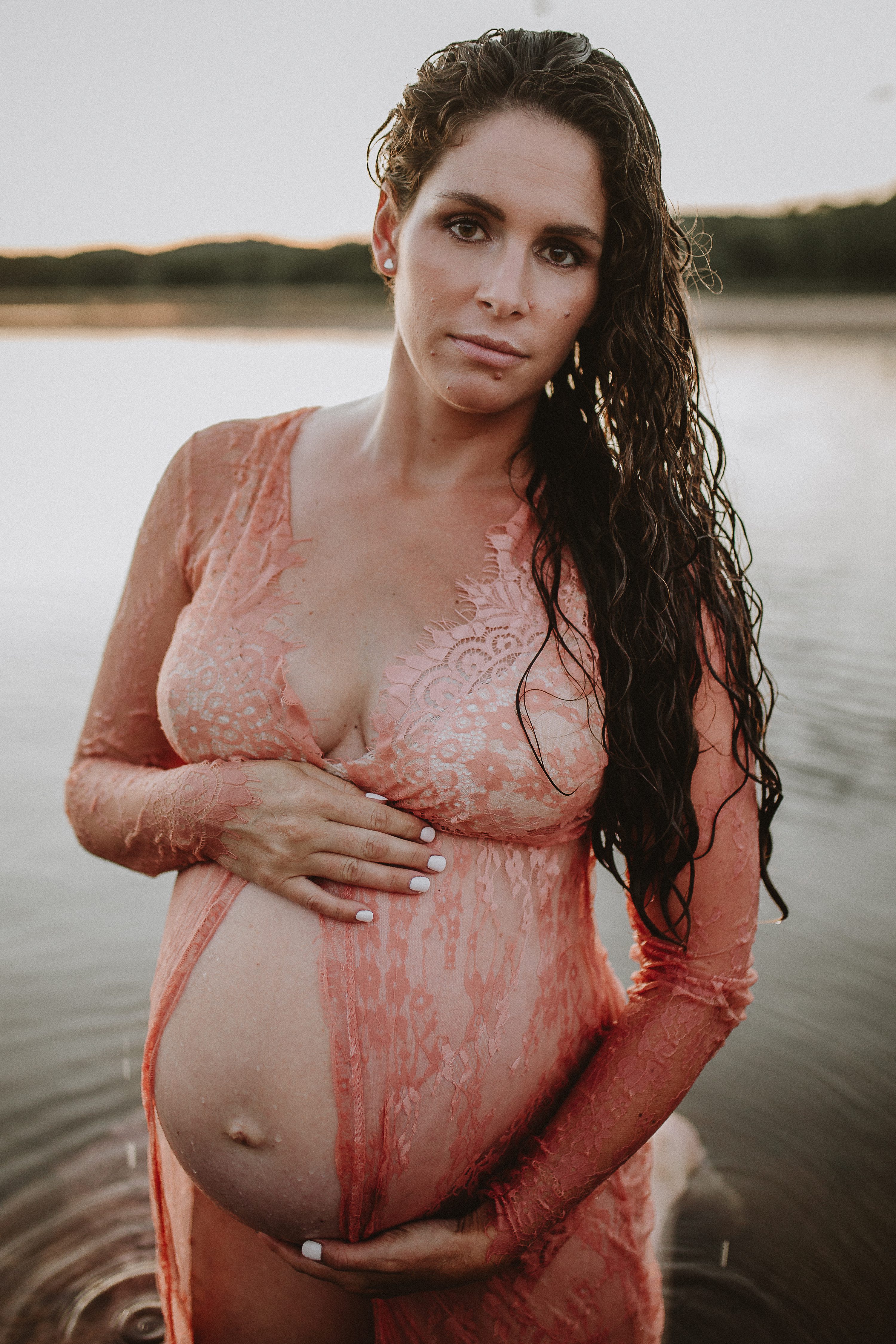 Maternity session by the river,Pregnant mother in a lace gown by the beach,PPregnant mother in a peach, lace gown by the water.,Pregnant mother in a long, lace gown holding her belly.,Pregnant woman in a peach gown near the river at sunset.