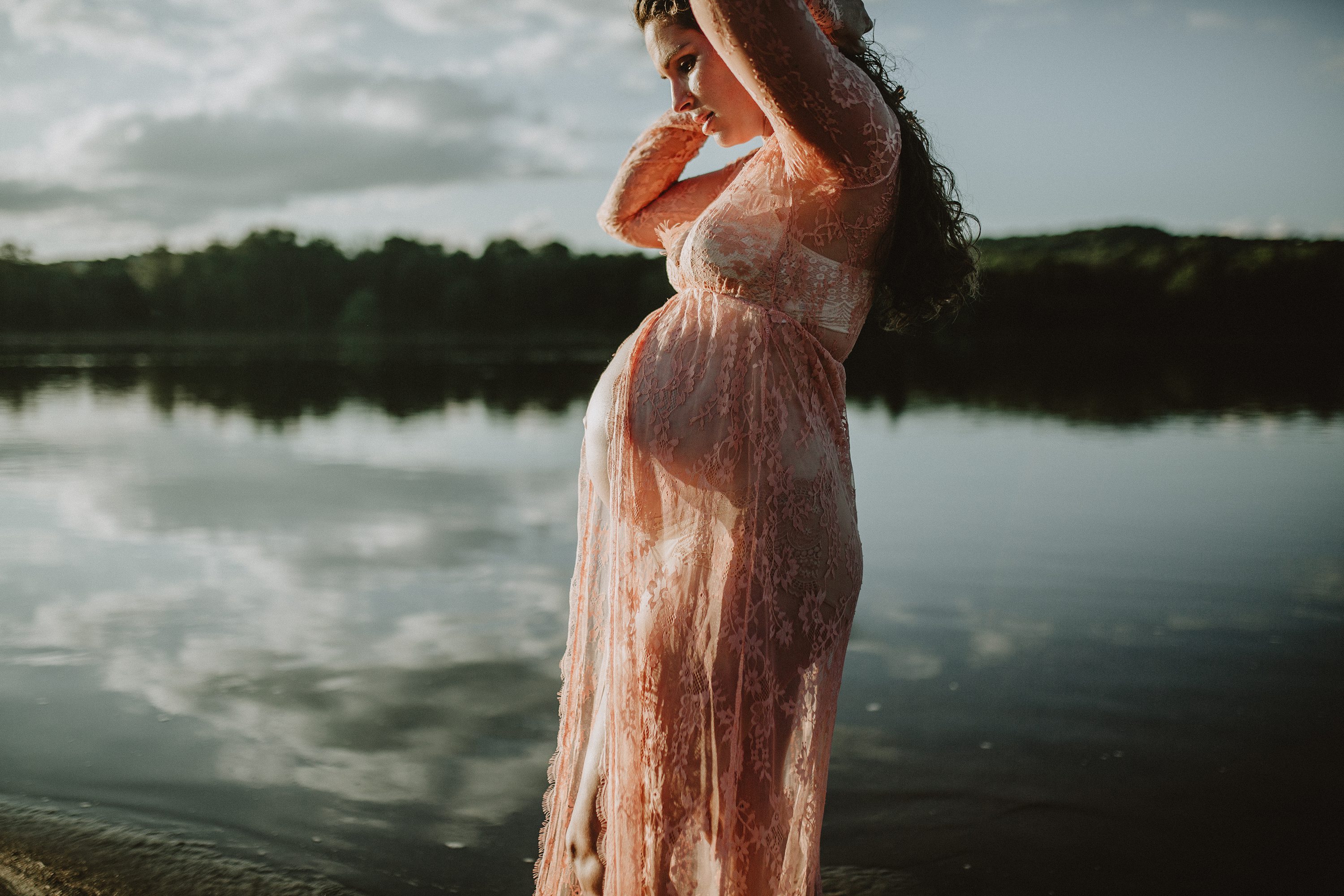 Maternity session by the river,Pregnant mother in a lace gown by the beach,PPregnant mother in a peach, lace gown by the water.,Pregnant mother in a long, lace gown holding her belly.,Pregnant woman in a peach gown near the river at sunset.