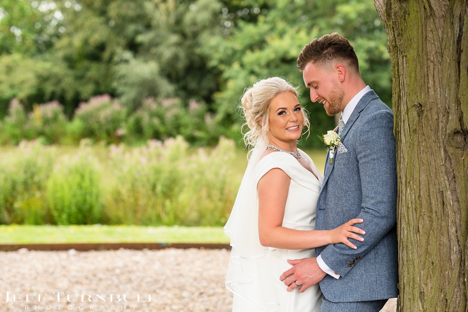 Villiers Barn Wedding Photography,Essex Wedding Venue,Bride and Groom Leaning against a Tree