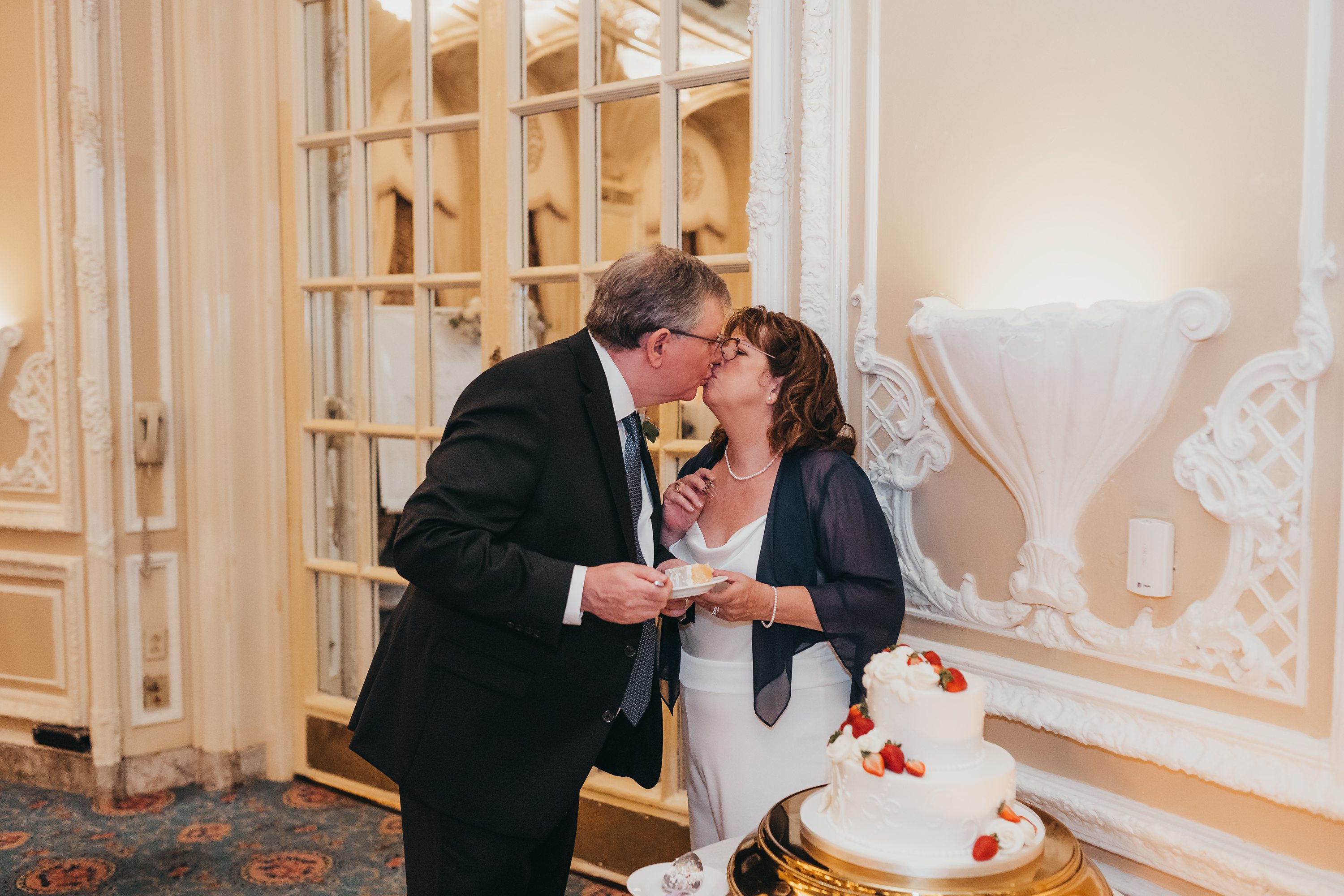 Boston Wedding Photographer,socially distanced wedding,dessert works bakery boston,white wedding cake with strawberries,couple kissing after cutting wedding cake